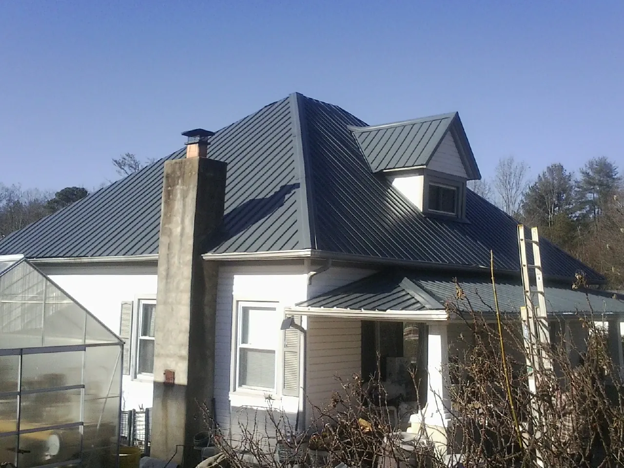 Dark blue standing seam metal roof on a white farmhouse with dormer — Slate & Tile Roof Repair by Roofing Brothers in Acworth