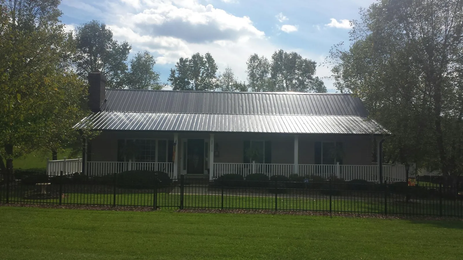 Gray metal roof on a brick ranch with a full width front porch — Gutter Guard Installation work by our crew in Acworth